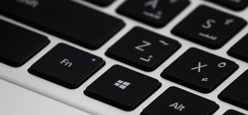 Close-up of black laptop keys with small Arabic letters printed beside the English Z, X, A and S