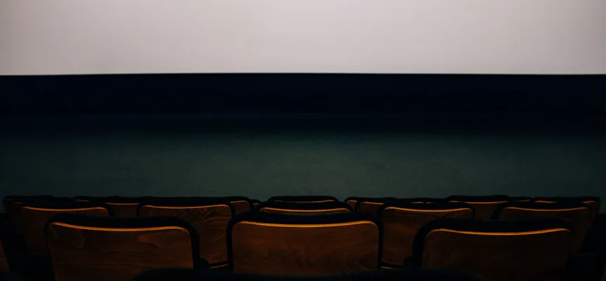 Rows of empty wooden cinema seats facing a blank screen