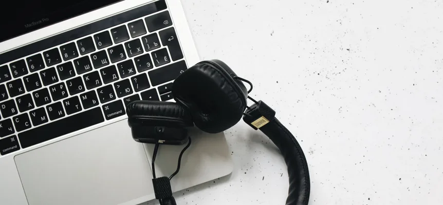 Black over-ear headphones resting on an open laptop, seen from above