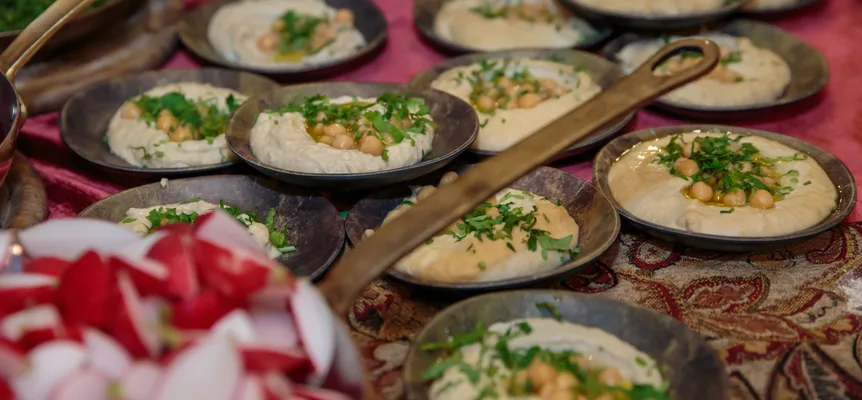 A spread of hummus, bread and small mezze dishes on a wooden table