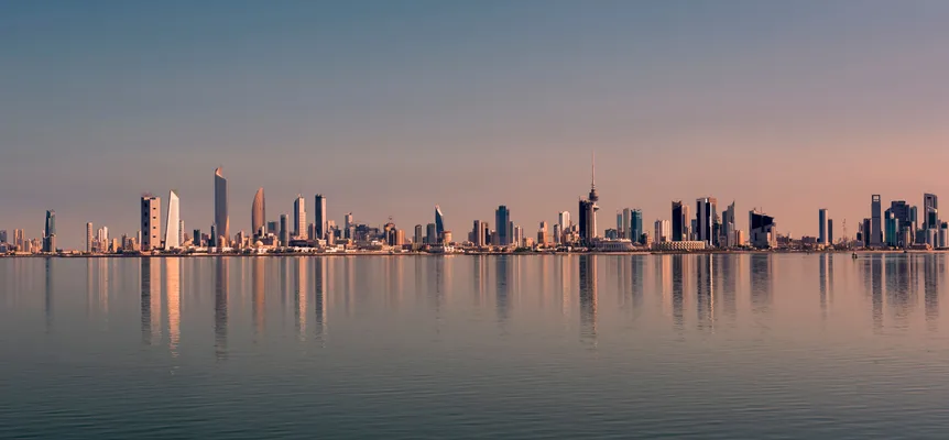 Kuwait City's towers reflected in calm water at sunset