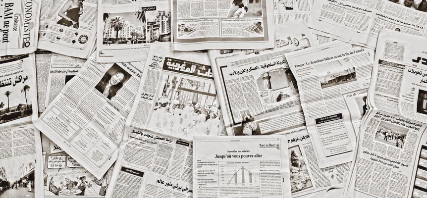 Dozens of Moroccan newspapers in Arabic and French spread out and overlapping, their headlines and photos in sepia tones