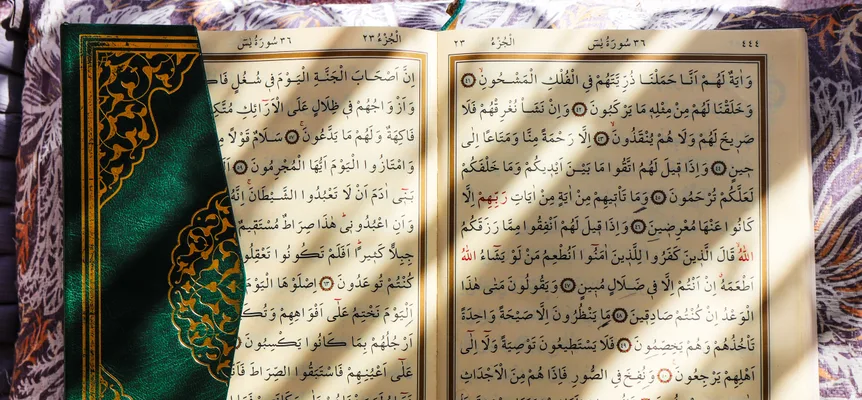 An open Quran in sunlight, its Arabic script visible across both pages